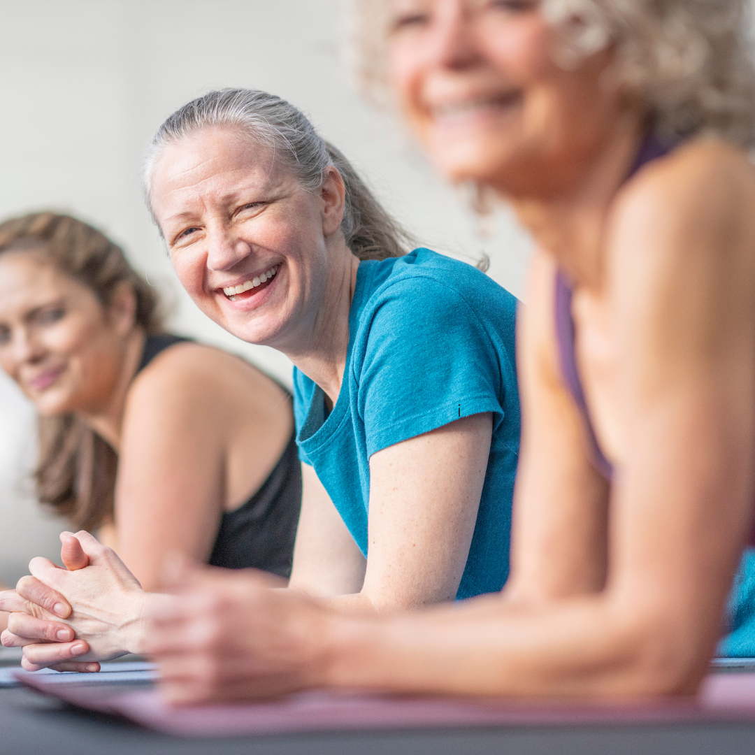 Group of women smiling together on yoga mats during a Hybrid Yoga and Women’s Health Training in Ireland