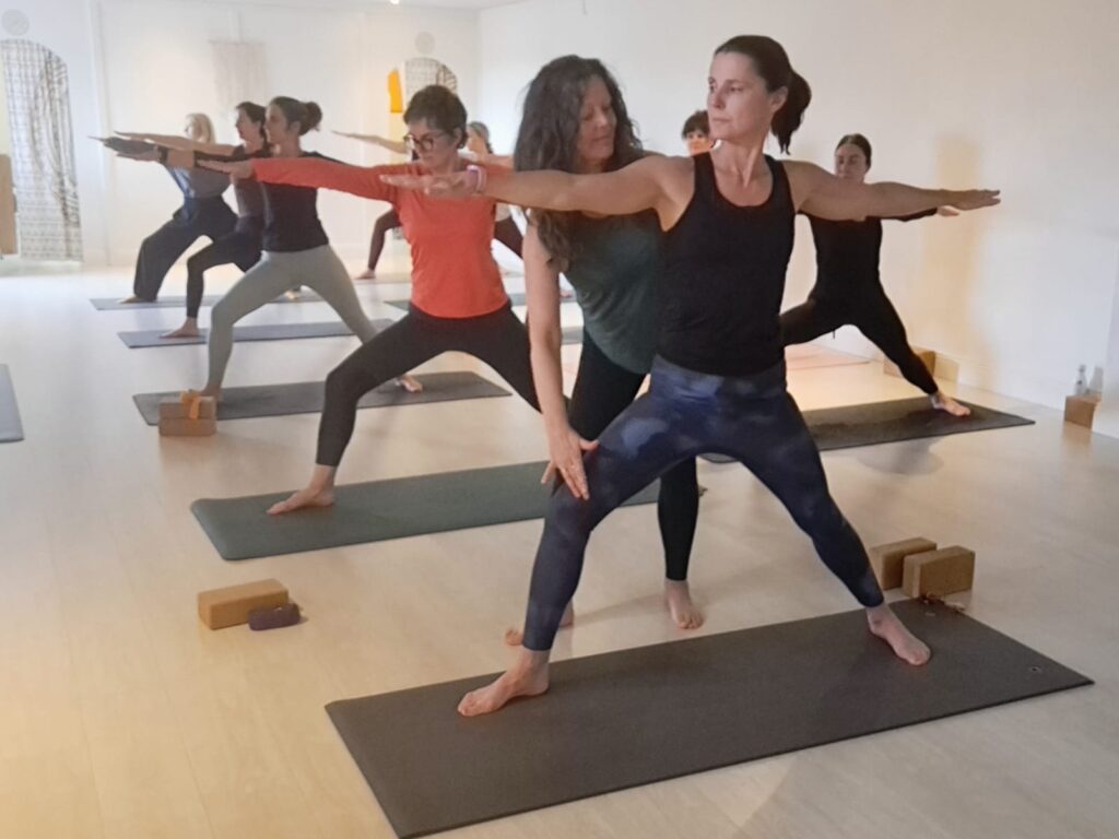 200 hr Yoga Teacher Training Galway – Carol Murphy adjusting Warrior II in a Progressive Vinyasa yoga teacher training class